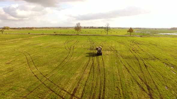 The tractor is stacking haystacks on an agricultural field in autumn, aerial view