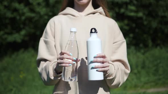 Young Beautiful Woman Is Showing Water Bottles While Standing in City Park on Summer Spbd