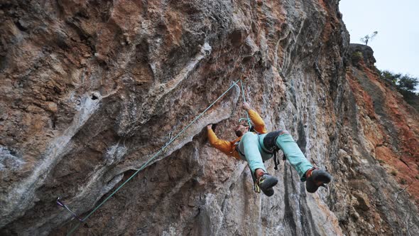 Slow Motion Smiling Tired Man Rock Climber Hanging on Rope on Hard Challenge Route on Overhanging