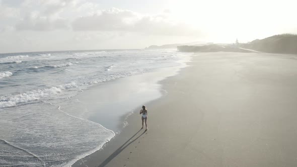 Aerial View of a woman walking on the beach, Praia do Areal, Azores, Portugal.