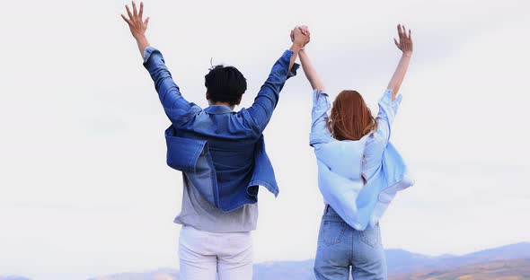 Romantic Asian couple walking and holding hands together on mountain background.