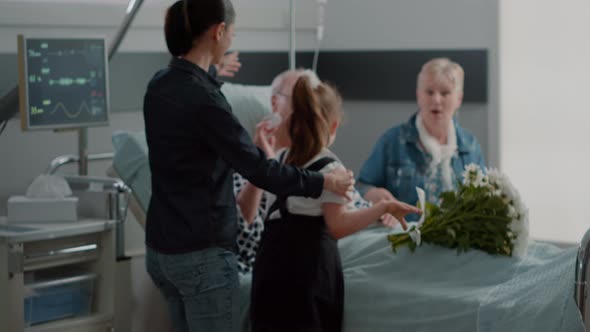 Close Up of Mother and Kid Surprising Grandpa with Visit in Hospital Ward