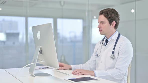 Focused Young Male Doctor Working on Desk Top