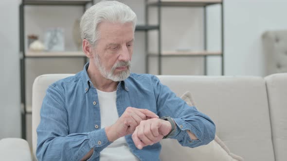 Old Man Using Smartwatch While Sitting on Sofa
