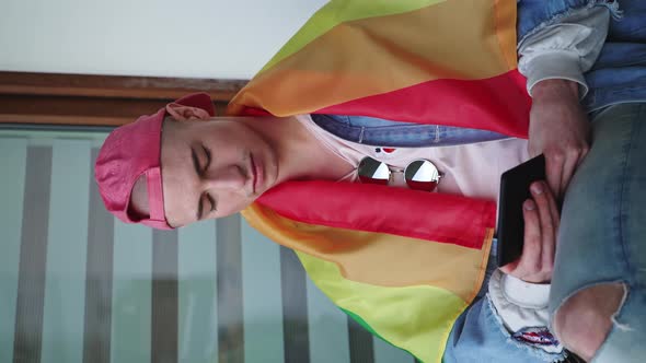 Vertical Shot of a Caucasian Gay Man with a Red Cup on His Bald Head and Rainbow Flag on His