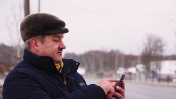 Business Man with a Mustache Makes a Message Online on a Smartphone