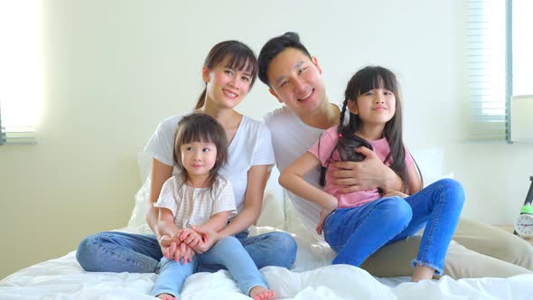 Portrait of Asian happy family smile and look at camera on bed together in bedroom at home.