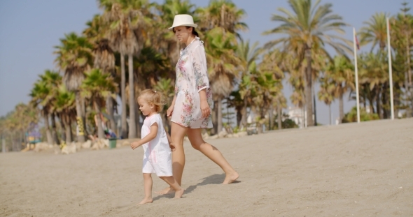 Mother Walking On a Beach With Her Small Daughter