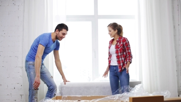 Smiling Couple Unpacking Box With New Sofa At Home