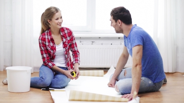 Happy Couple Measuring Wallpaper At Home alt