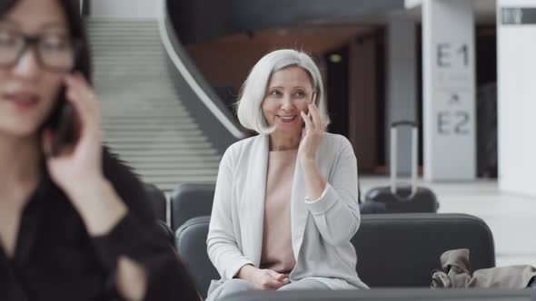 Diverse Passengers with Smartphones Waiting in Departure Lounge