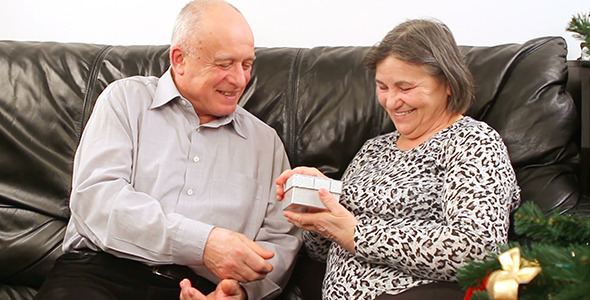 Senior Couple with Gift near Christmas Tree