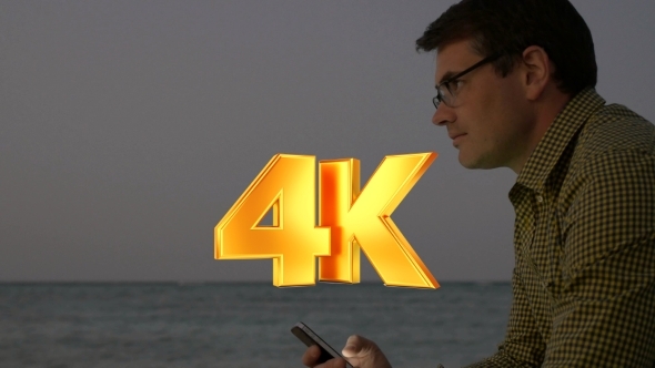 Young Man Using Smart Phone By Sea In The Evening alt