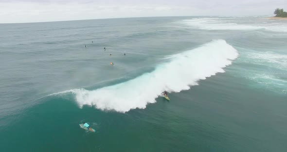 Aerial view of a surfer gracefully surfing in front of a big wave