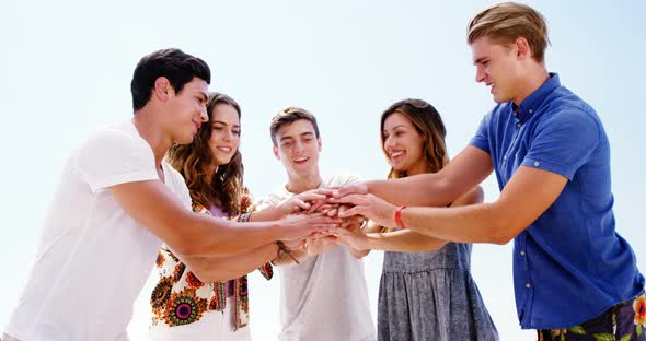 Friends forming hand stack at beach