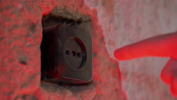 A Man Sticks His Finger Into the Socket Under Red Lighting Closeup