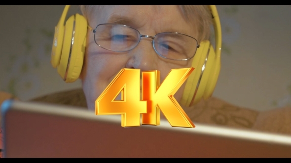 Senior Woman In Headphones Using Tablet Computer