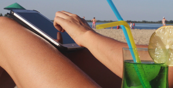 Blonde Girl Using Touchpad on the Beach