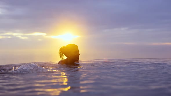 Lovely Female Relaxed and Plunged Into Infinity Pool During Golden Sunset