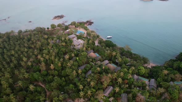 jungle island resort in thailand's andaman sea during sunset with turquoise blue water, aerial
