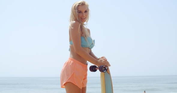 Pretty Woman Holding Her Skateboard At The Beach