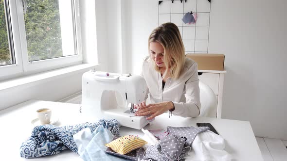 Businesswoman using sewing machine sitting at table