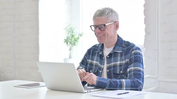 Cheerful Casual Middle Aged Man Doing Video Chat on Laptop