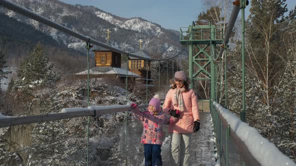 Little Girl with Mom on Winter Suspension Bridge