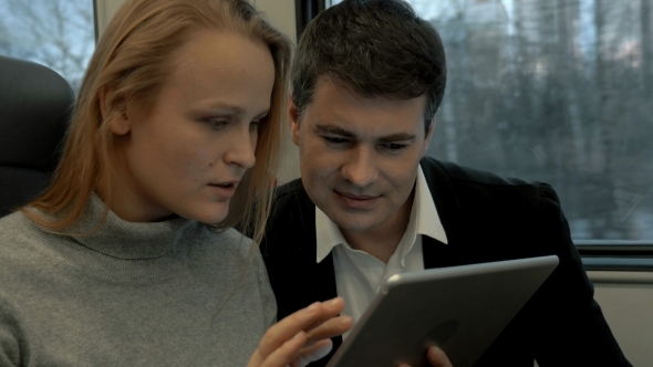 Friends Passing Time In Train With Tablet PC alt
