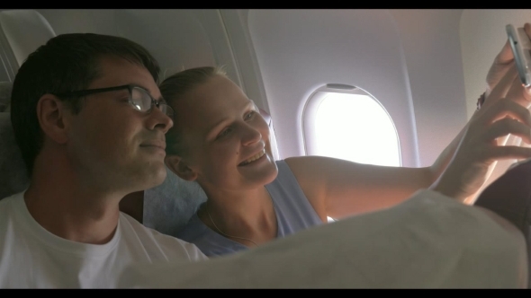 Young Couple Making Selfie With Cell In Plane alt