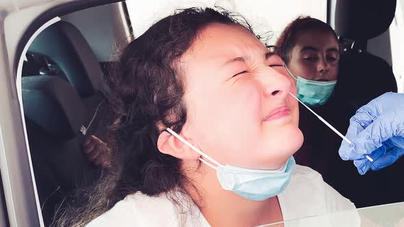 Pediatrician Taking Nasal Mucus Test Sample From Elementary Age Girl's Nose Performing Respiratory