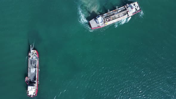 Two large sand dredging vessels positioned in a city shipping channel to re built up sand from the w