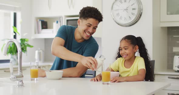 Happy biracial father and daughter eating breakfast together