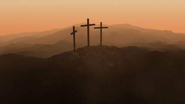 Atmospheric, dark image of three crosses silhouetted on the top of a mountain.