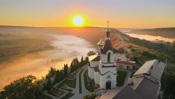 Aerial drone view of the Old Orhei at sunset. Valley with river and fog, monastery located on a hill