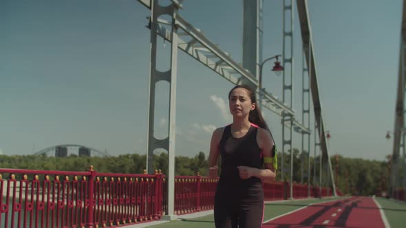 Asian Female Jogger Running on Pedestrian Bridge