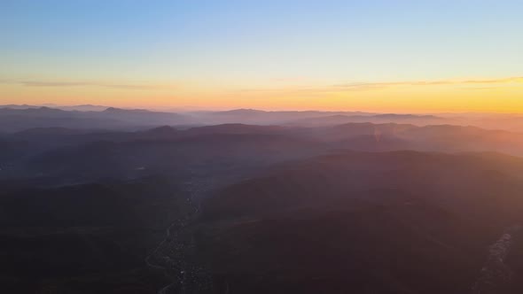 Aerial View of Dark Mountain Hills with Bright Sunrays of Setting Sun at Sunset