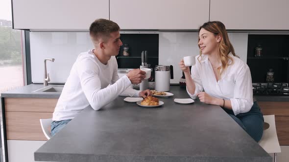 Smiling Couple Drinking Coffee in the Kitchen at Home