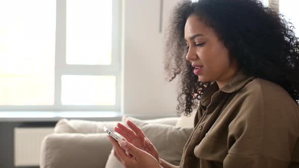 Satisfied Biracial Young Curly Woman Holding Smartphone Enjoy Using New Mobile Application