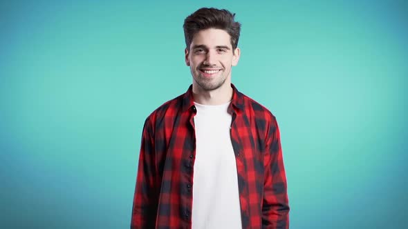 Handsome european man with trendy hairdo in red plaid shirt on blue studio background. 