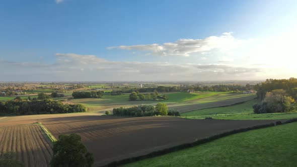 Aerial view of a field in the countryside at sunset. village in the distance to the left, there are