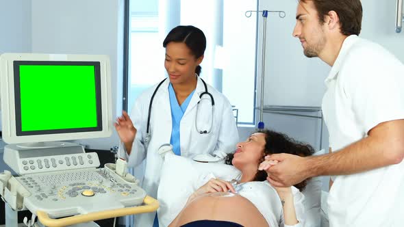 Doctor showing sonography report to pregnant woman on monitor