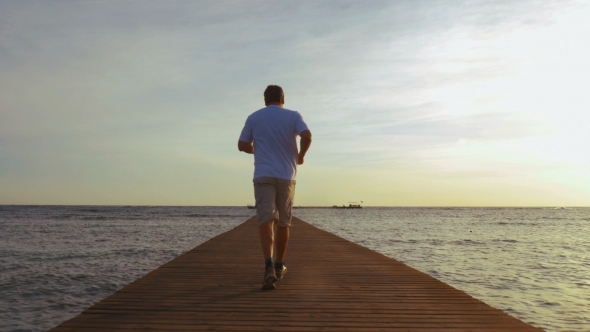 Man Jogging On The Pier At Sunset alt
