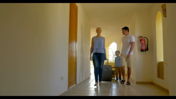 Family With Rolling Bags In Hotel Corridor alt