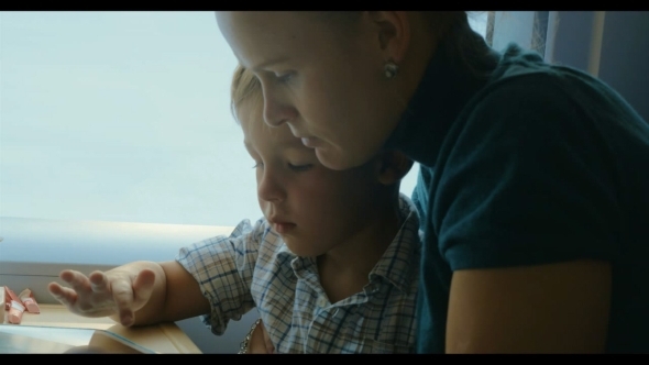 Mother And Son Passing Time In Train With Tablet alt