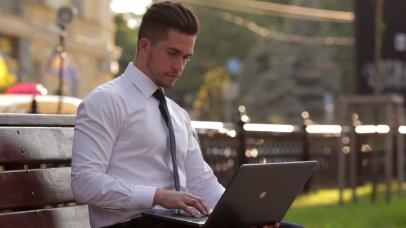Young Man Working With a Laptop In Park alt