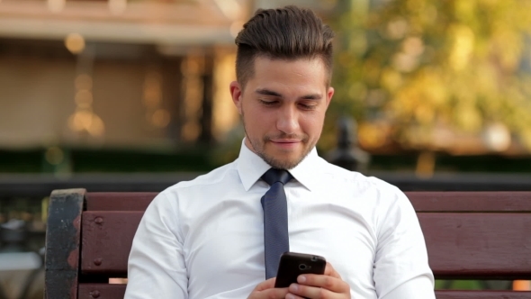 Young Businessman Sitting On a Bench On The Street alt