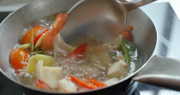 Cook with tom yum soup in kitchen