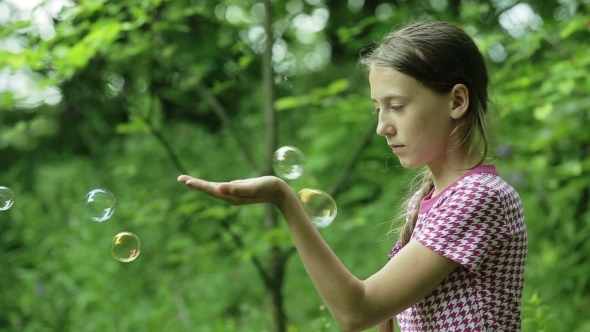 Young Girl Catches Soap Bubbles In The Park alt