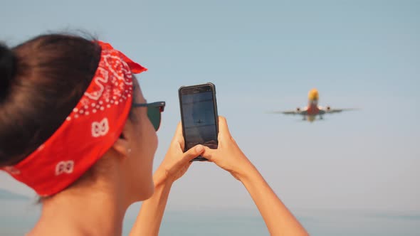 Yound Tourist Woman Making Video of Landing Airplane at Tropical Beach. Phuket, Thailand. Slowmotion